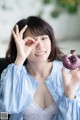 A woman holding a purple donut in front of her eyes.