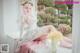 A woman in a wedding dress sitting on a window sill.