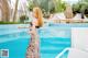 A woman in a long dress standing by a swimming pool.