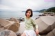 A woman sitting on a rock by the ocean.