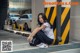 A woman sitting on the ground in front of a parking garage.