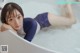 A woman laying in a bathtub with her legs up in the water.