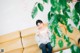 A woman sitting on a couch in front of a plant.