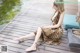 A woman in a leopard print dress sitting on a wooden dock.