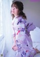 A young girl in a kimono sitting on a bed.